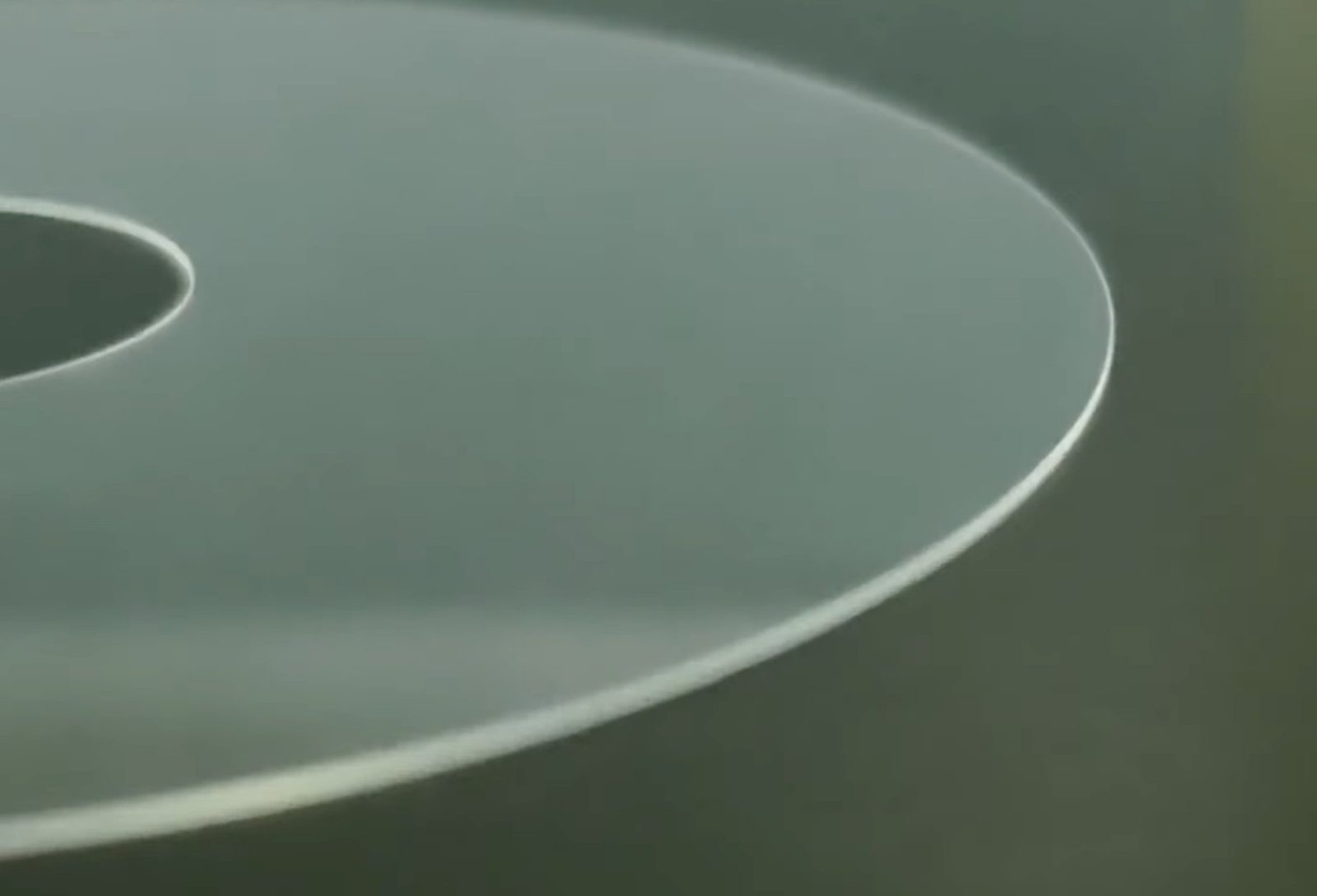 A finished GlaCE glass disk, its inner hole and outer edge catching the light